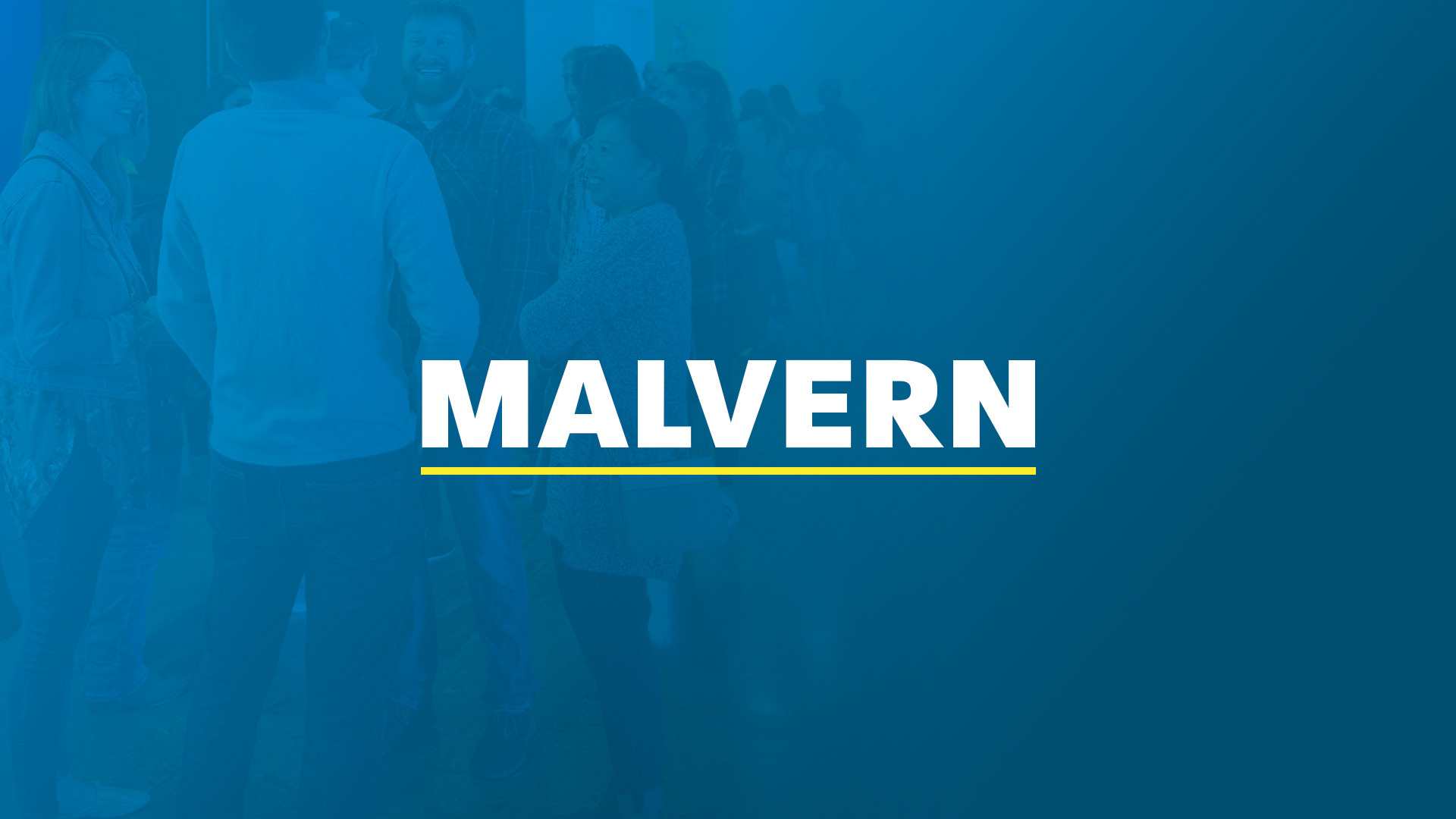 Four young people smiling together in front of the words ‘Penn State,’ written in white and underlined in yellow